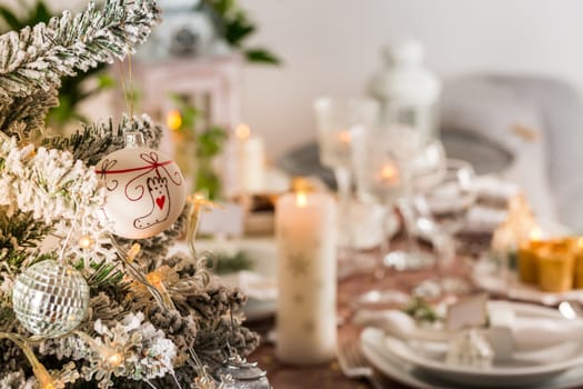 Table setting for celebration Christmas and New Year Holidays. Festive table at home with Christmas tree.