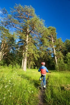 Boy on bike in helmet riding in the forest