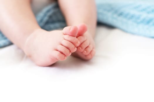Baby feet on white background with blue blanket