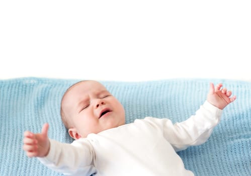 Baby boy crying on blue blanket on white background