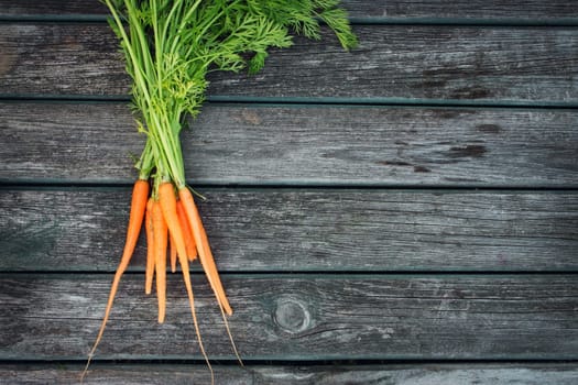 small orange carrots on old wooden board