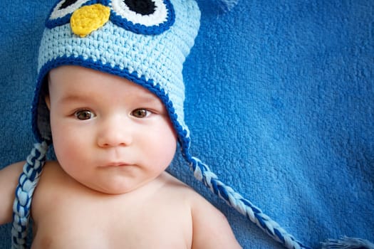 four month old baby in owl hat on a towel