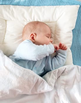 Four month old baby sleeping on blue blanket