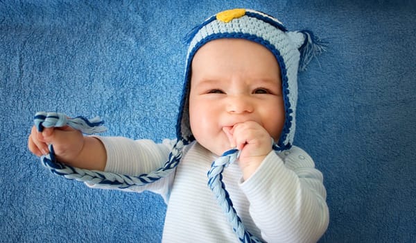 four month old baby in owl hat on a towel