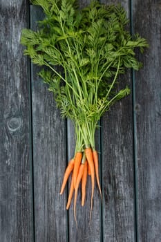 small orange carrots on old wooden board