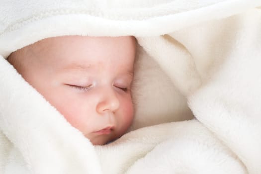 little boy sleeping on soft white blanket