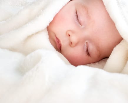 little boy sleeping on soft white blanket