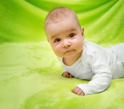 little boy lying on soft green blanket