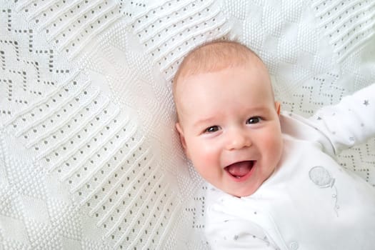 little boy lying on soft white blanket
