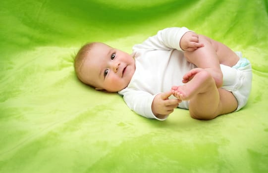 little boy lying on soft green blanket
