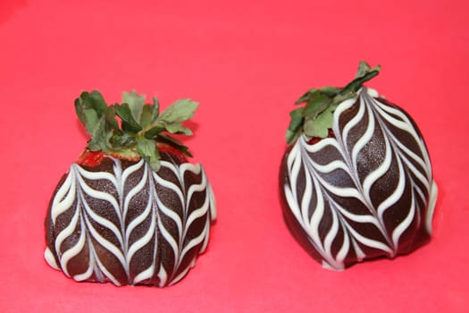 Chocolate covered strawberries with white icing on a pink background