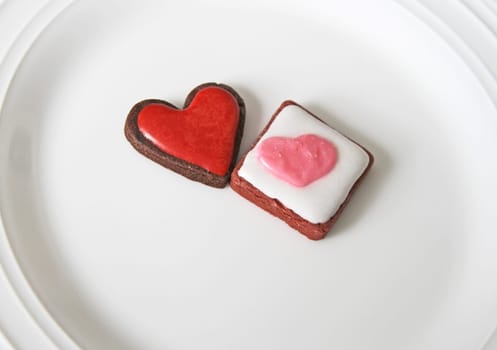 Heart cookies in different shapes with icing on top on a white plate