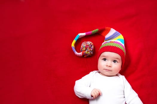 Baby in red and white hat on the bed
