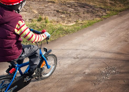 Boy on bike at gravel road in spring