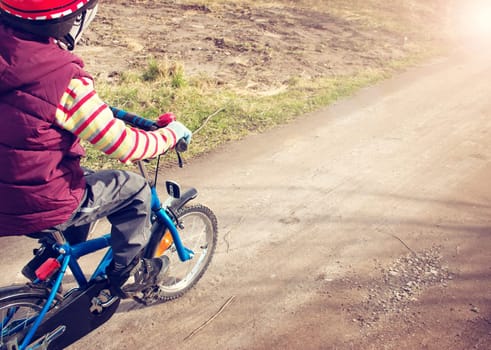 Boy on bike at gravel road in spring