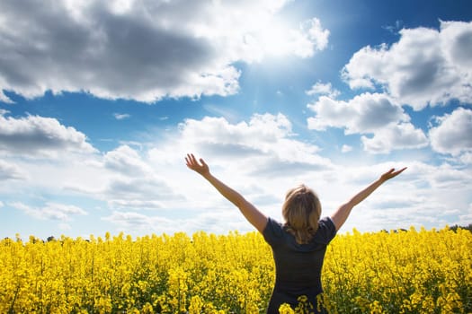 Young woman on field with yellow flowers