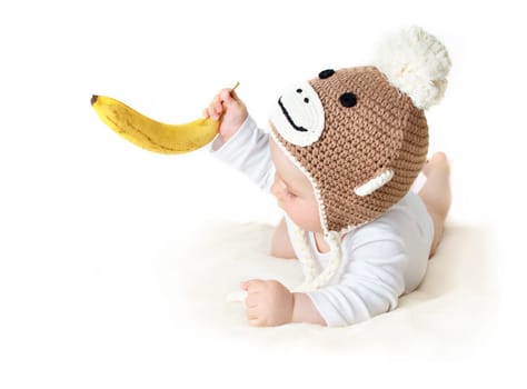 little baby in knitted montey hat on brown blanket