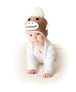little baby in knitted montey hat on brown blanket