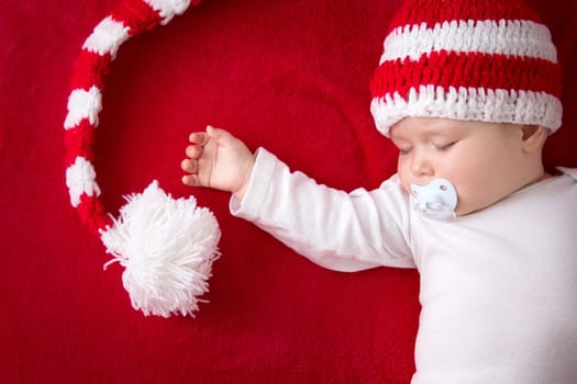 little baby in knitted red whitey hat on red blanket
