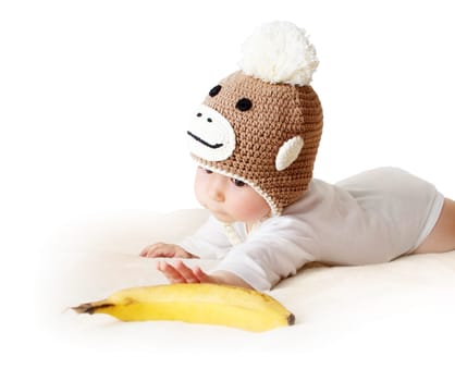 little baby in knitted montey hat on brown blanket