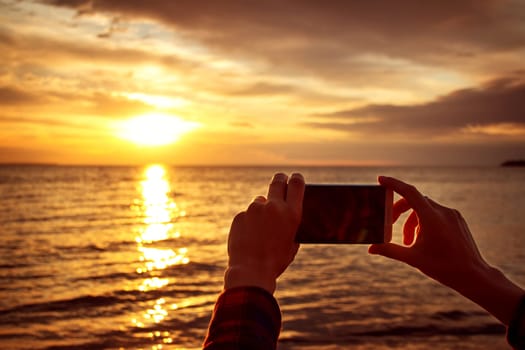 woman hands holding mobile phone at sunset