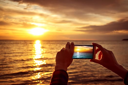 woman hands holding mobile phone at sunset