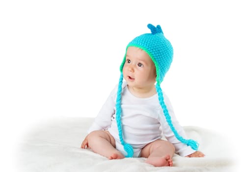 little baby in knitted dinosaur hat on soft blanket