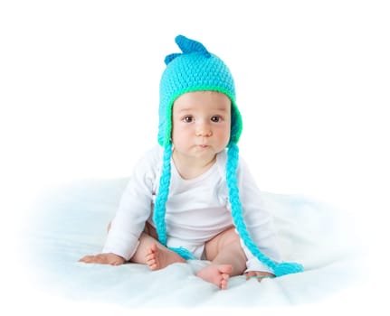 little baby in knitted dinosaur hat on soft blanket