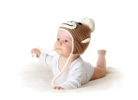 little baby in knitted montey hat on brown blanket