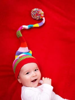 Baby in red and white hat on the bed