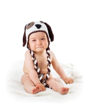 sad baby in dog hat sitting isolated on white background