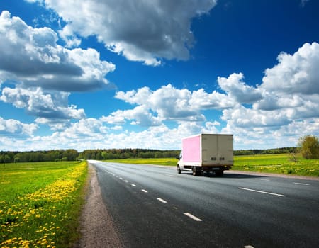 asphalt road on dandelion field with a small truck