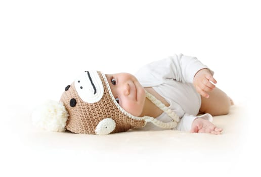 little baby in knitted montey hat on brown blanket