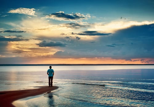 Alone man stamding at the sea in twilight