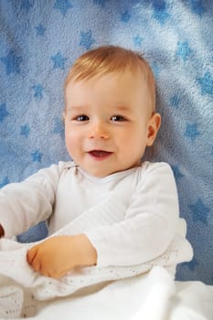 One year old baby lying on blue towel with stars