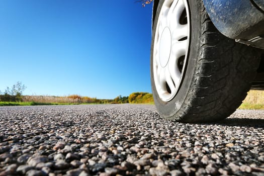 Car wheel on asphalt road in autumnal evening