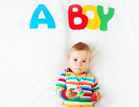 Baby boy lying on soft blanket with letters above
