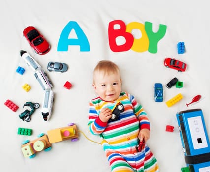 Baby boy lying on soft blanket with letters above