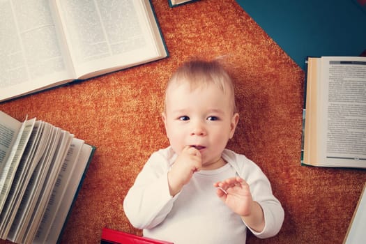 One year old baby among books on a blanket
