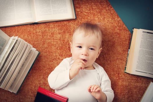 One year old baby among books on a blanket