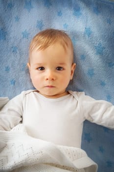 One year old baby lying on blue towel with stars