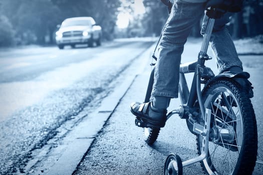 A boy on bike and a car on the road