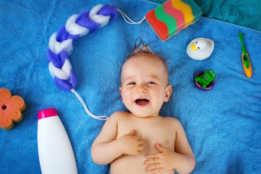 one year old baby lying on towel with washing tools