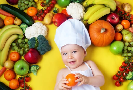 baby in chef hat surrounded wyh fruits and vegetables on yellow blanket