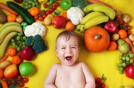 baby surrounded with fruits and vegetables on yellow blanket