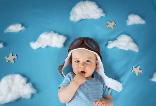 boy lying on blanket with white clouds in pilot hat