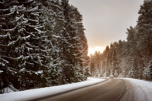 car in snowy winter evening at asphalt road