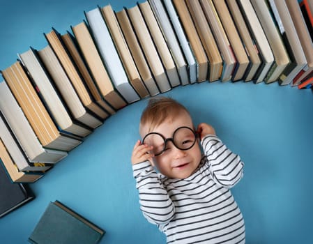 One year old baby among books with spectackle