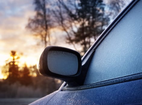 Car window and side mirror covered with ice in early morning
