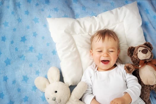 One year old baby lying in bed with alarm clock
